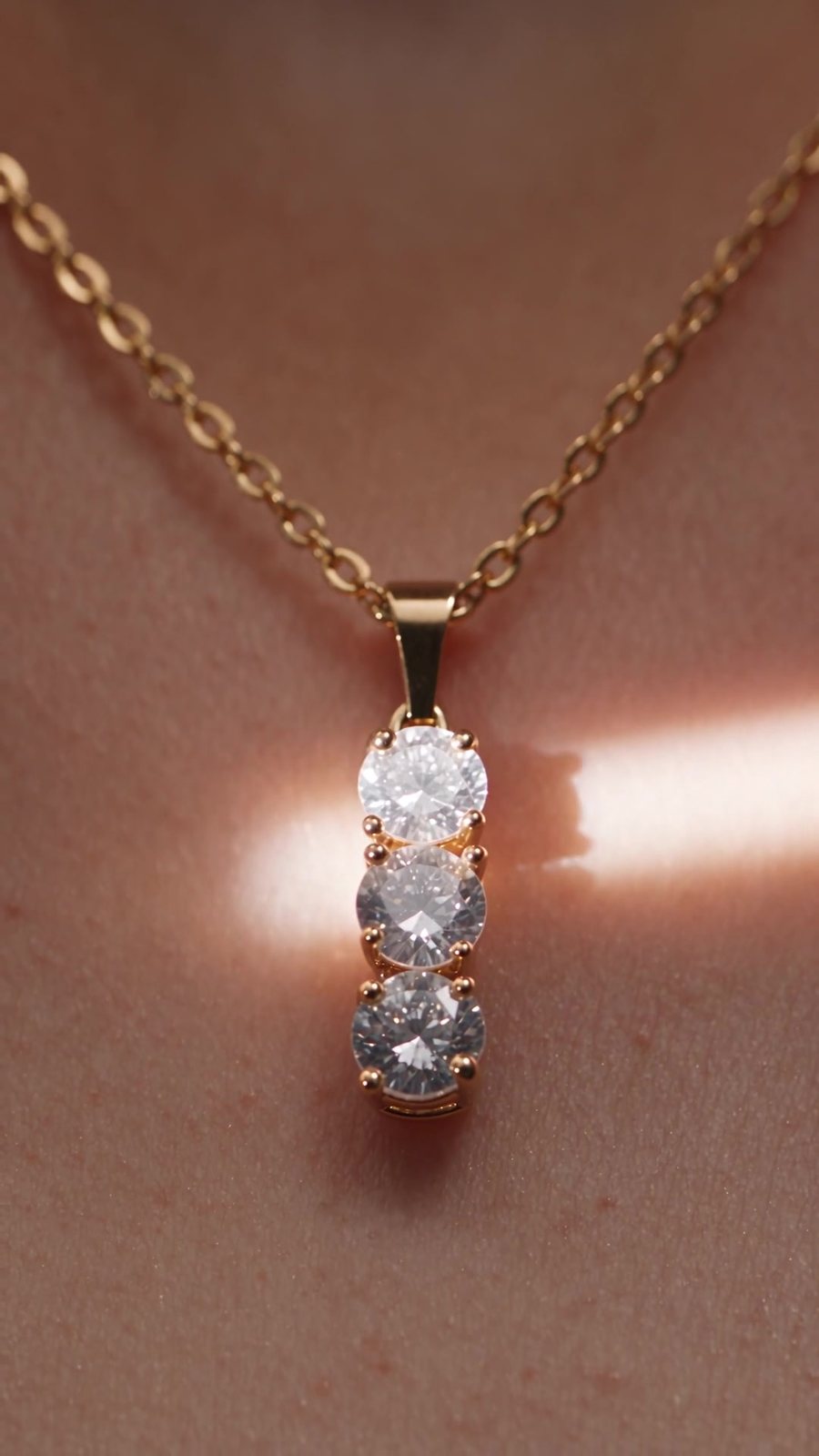 Cascade worn at the collarbone, with a band of warm light across the skin