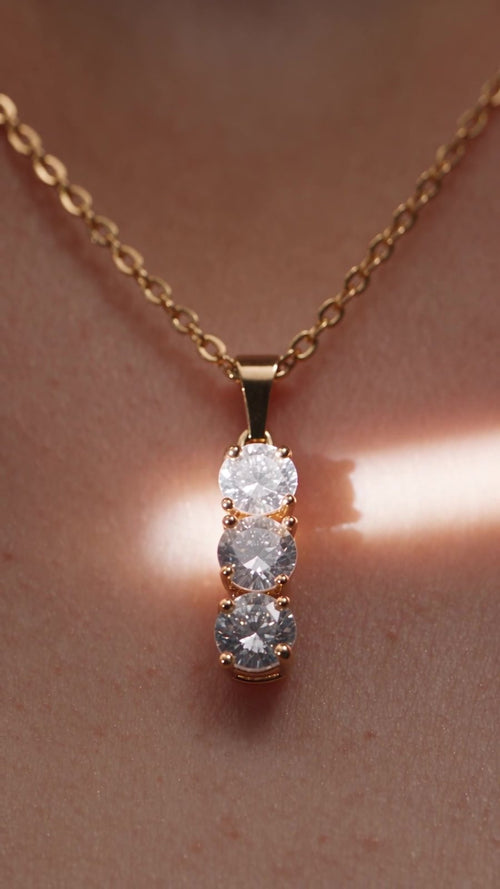 Cascade worn at the collarbone, with a band of warm light across the skin